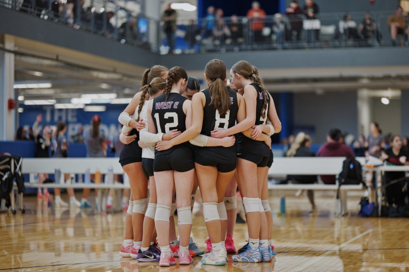 West E players in a team huddle on the court